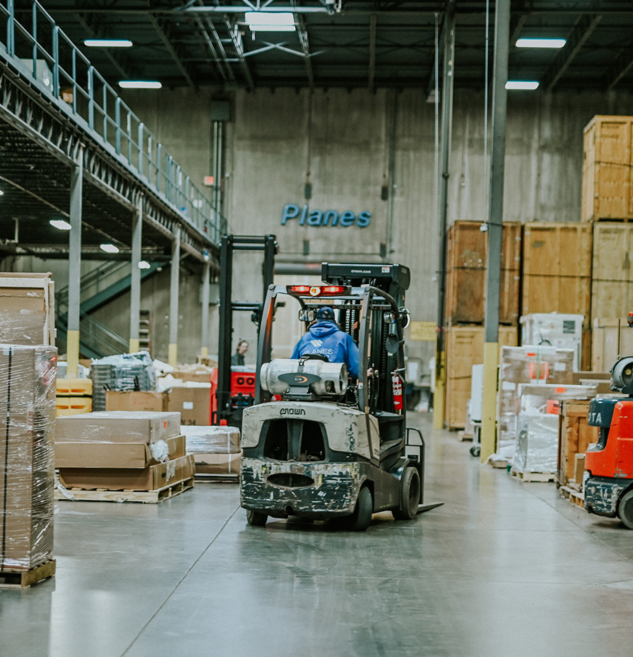 Employee driving forklift in warehouse